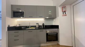 A modern kitchen with grey cabinets, a built-in microwave, a coffee maker, and an oven.