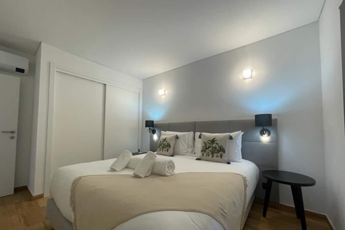 Un dormitorio moderno con una cama grande, lámparas de noche y una mesita.