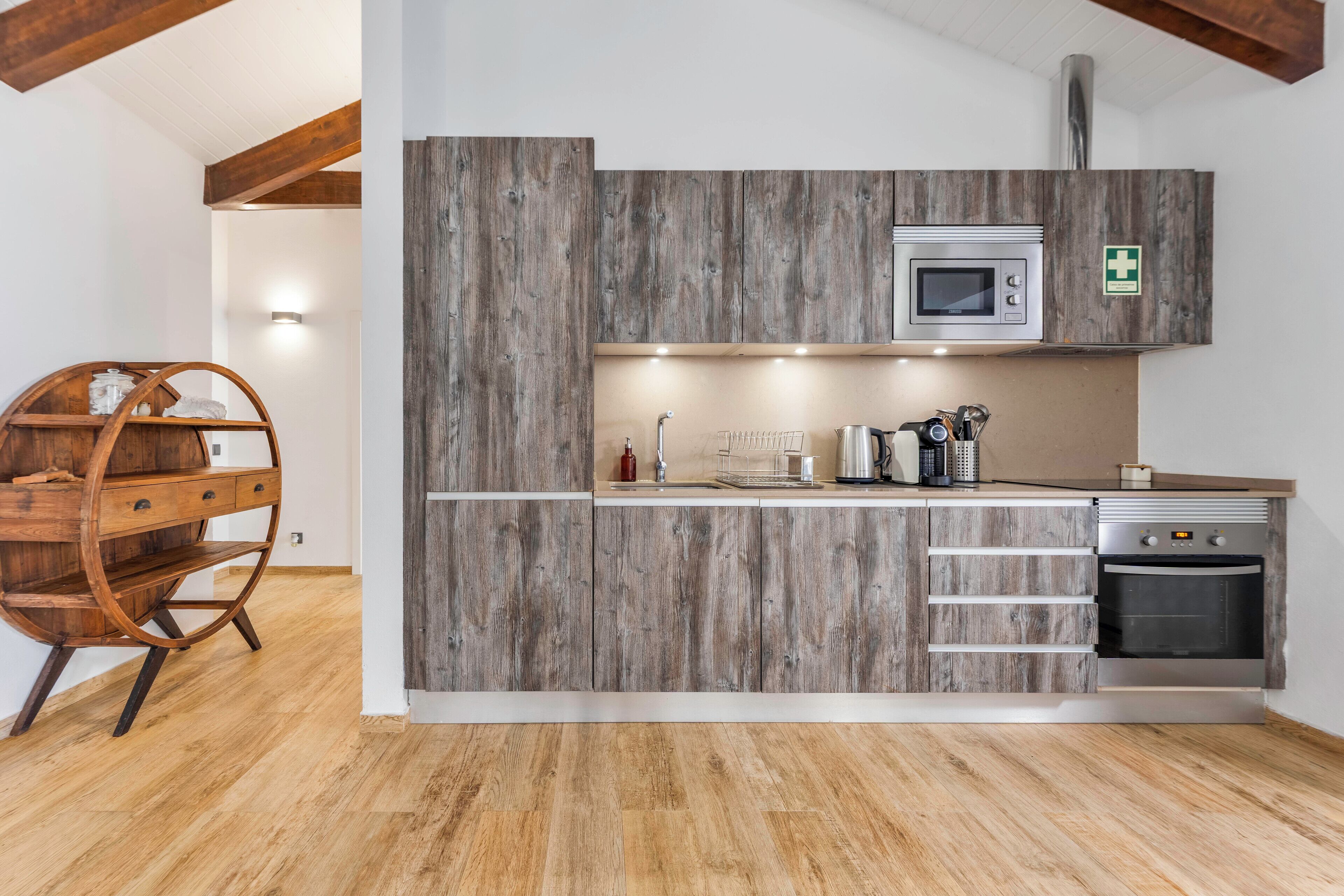 A modern kitchen with wooden cabinetry, a microwave, a sink, and a built-in oven.
