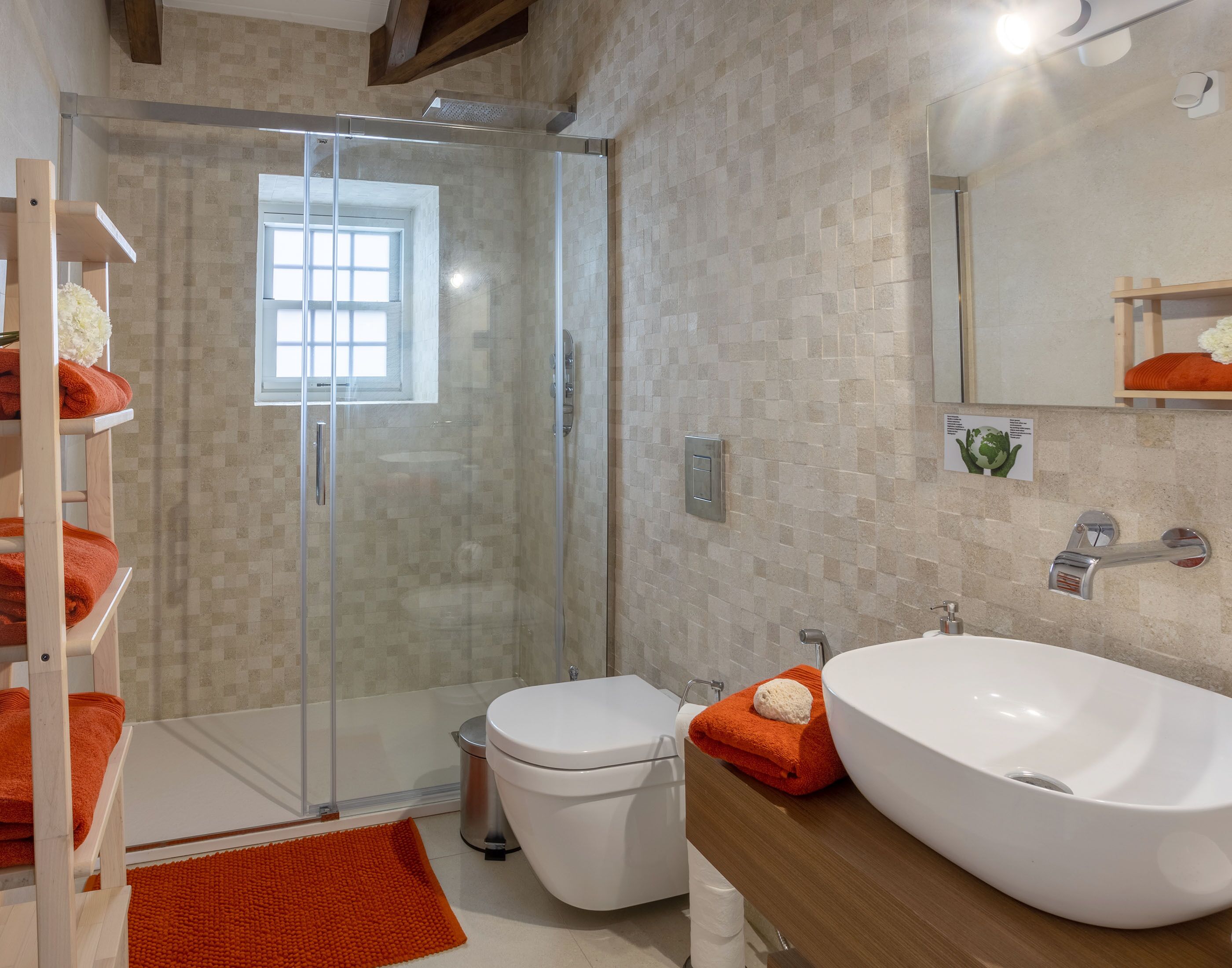 A modern bathroom with a glass-enclosed shower, a white toilet, and a large white sink.