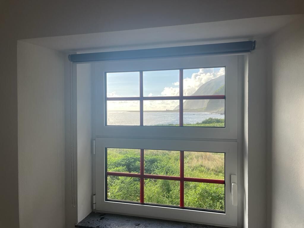 A room with a large window overlooking a coastal landscape.