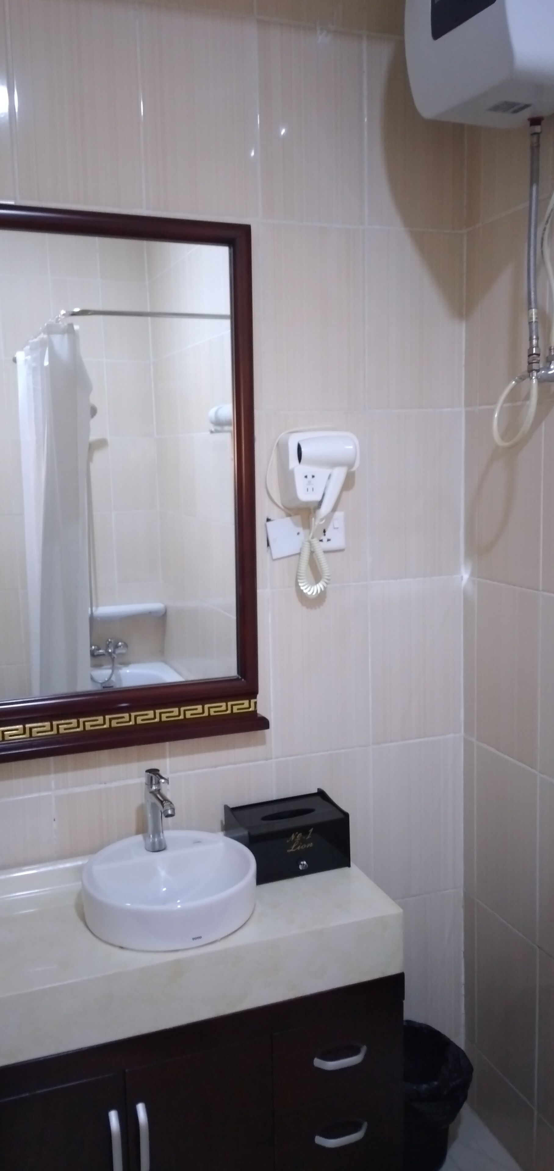 A bathroom with a white sink, a mirror with a decorative frame, a towel rack, and a handheld showerhead.