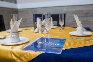 Una mesa con servilletas blancas, cristalería transparente y un menú que dice 'Lion Luxury Suites'.