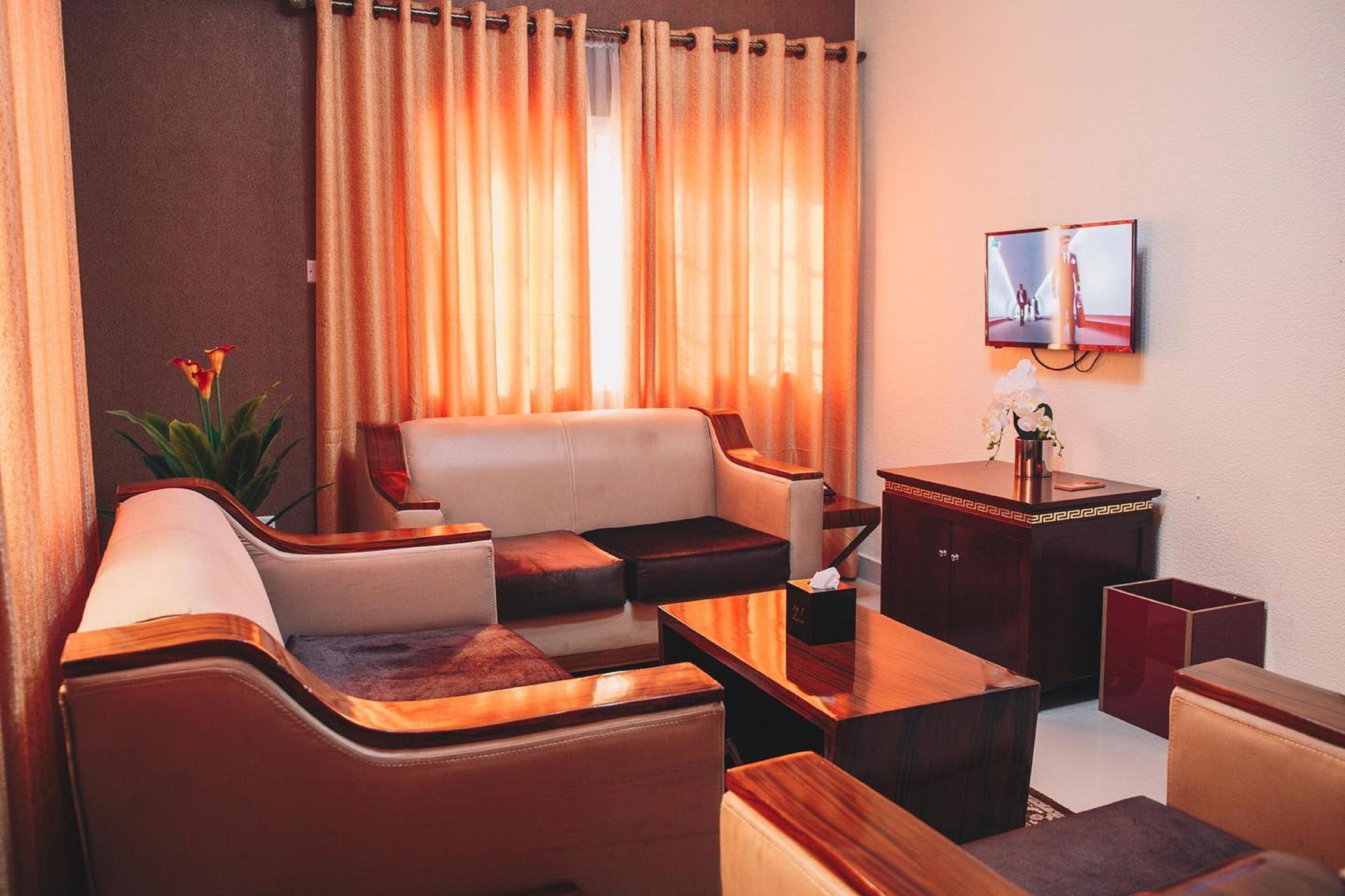 A modern living room with a sofa, coffee table, and side tables. A television is mounted on the wall.