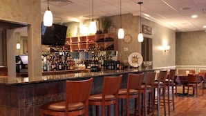 A bar area with wooden bar stools and a counter displaying various bottles. - Lion Luxury Suites (Enugu)