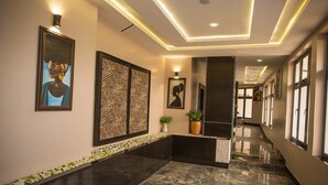A modern hotel lobby with a marble floor, wall art, and a reception desk. - Lion Luxury Suites (Enugu)