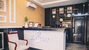 A reception area with a marble floor, a reception desk, a framed certificate, and a chair. - Lion Luxury Suites (Enugu)