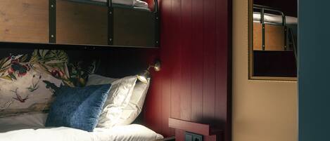 A bunk bed with a mural, a red wardrobe, and a small window.