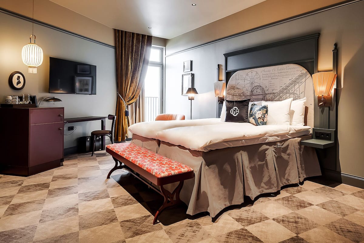 Une chambre d’hôtel avec un grand lit, un bureau, une banquette et une armoire.