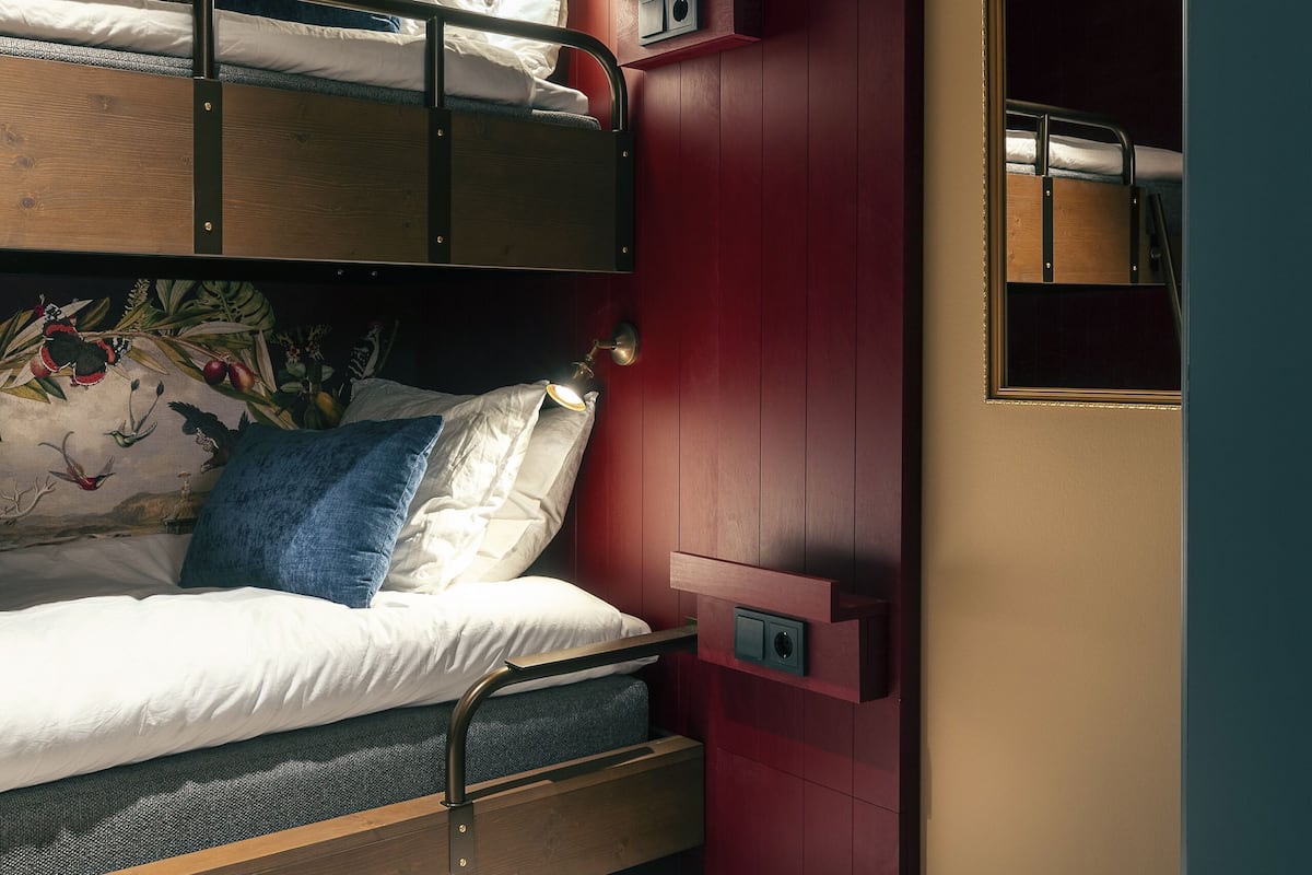 Un lit superposé orné d’une fresque murale, une armoire rouge et une petite fenêtre.