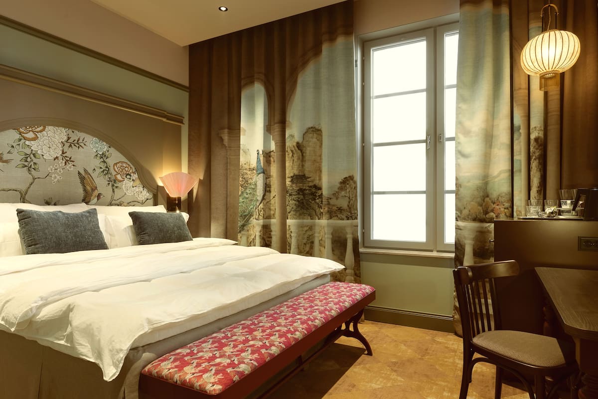 Une chambre à coucher avec un lit, un banc, une chaise et une table avec une lampe.