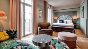 A modern bedroom with a bed, a chair, a round ottoman, and a sofa.
