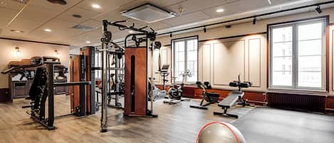Un gimnasio con diferentes equipos de ejercicio, una pelota grande para ejercicio y una pesa rusa.