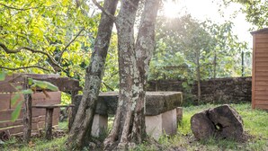 Un cadre extérieur rustique avec un banc en bois, un banc en pierre et un grand tronc d’arbre.