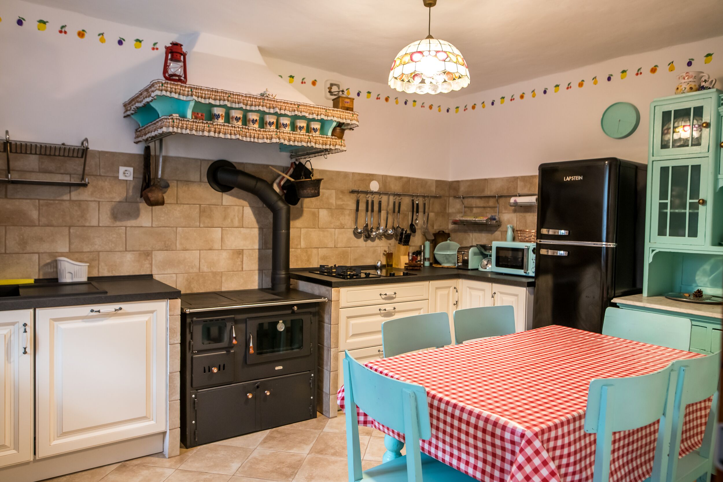 A kitchen with a stove, oven, microwave, refrigerator, and a table with chairs.