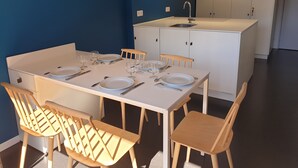 A dining area with a white table set for four, wooden chairs, a white cabinet with a sink, and a blue wall. - Location LES Arcs 1800 Residence Thuria (LES ARCS 1800)