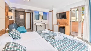 A modern hotel room with a large bed, a sitting area, a bathroom, and a TV. - Playa Ferrera Apartments (Felanitx)