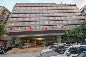 Un hôtel à plusieurs étages, doté d’une entrée imposante, d’un parking situé devant et offrant une vue dégagée sur la façade du bâtiment.