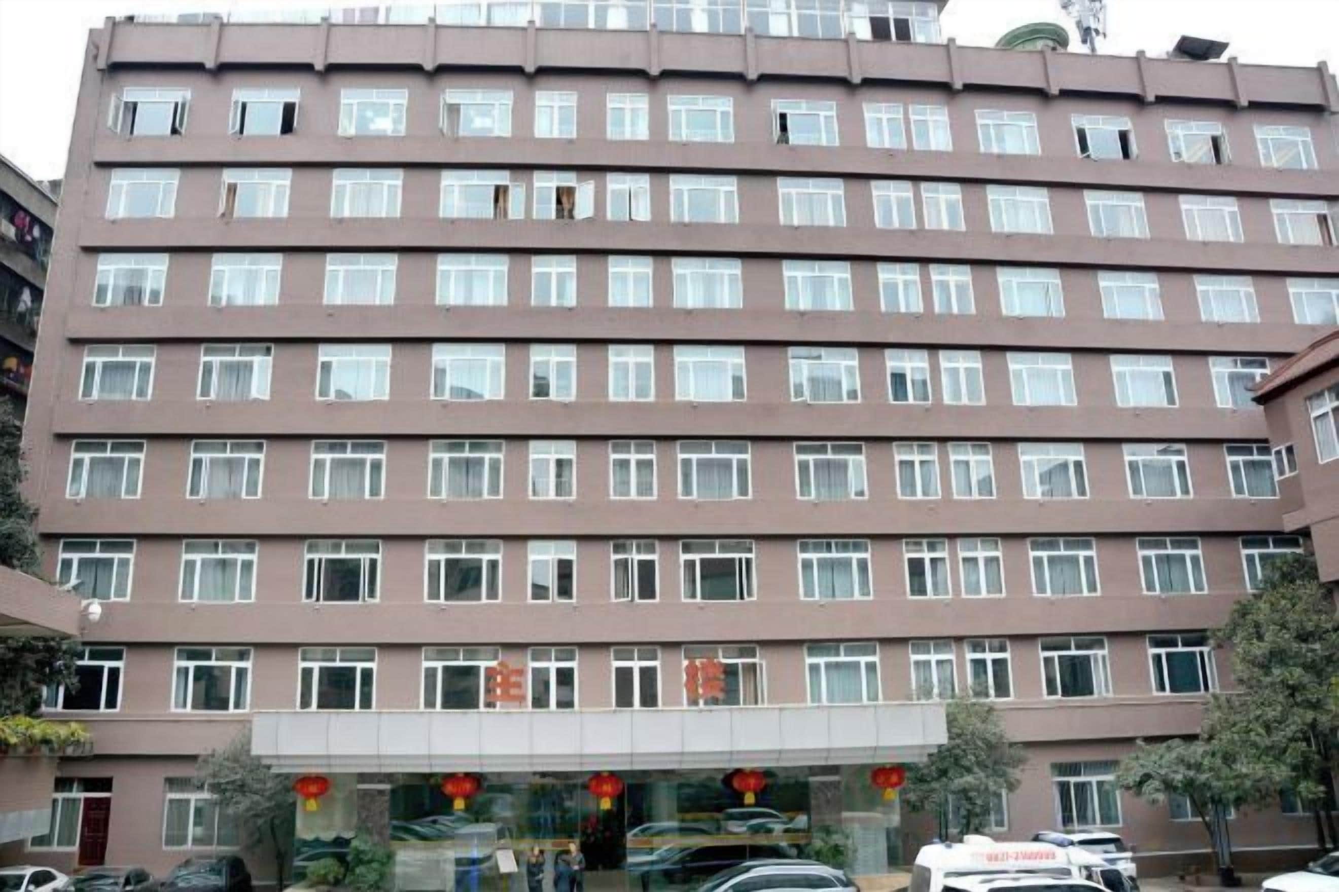 A multi-story building with a uniform facade, numerous windows, and a central entrance with a glass door.