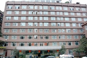 Un edificio de varios pisos con fachada uniforme, numerosas ventanas y una entrada central con puerta de cristal.