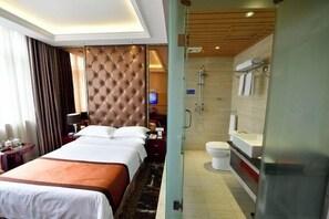 A hotel room with a large bed, a television, a bathroom with a shower, and a glass partition. - Donghua Hotel Bazhong (Bazhong)