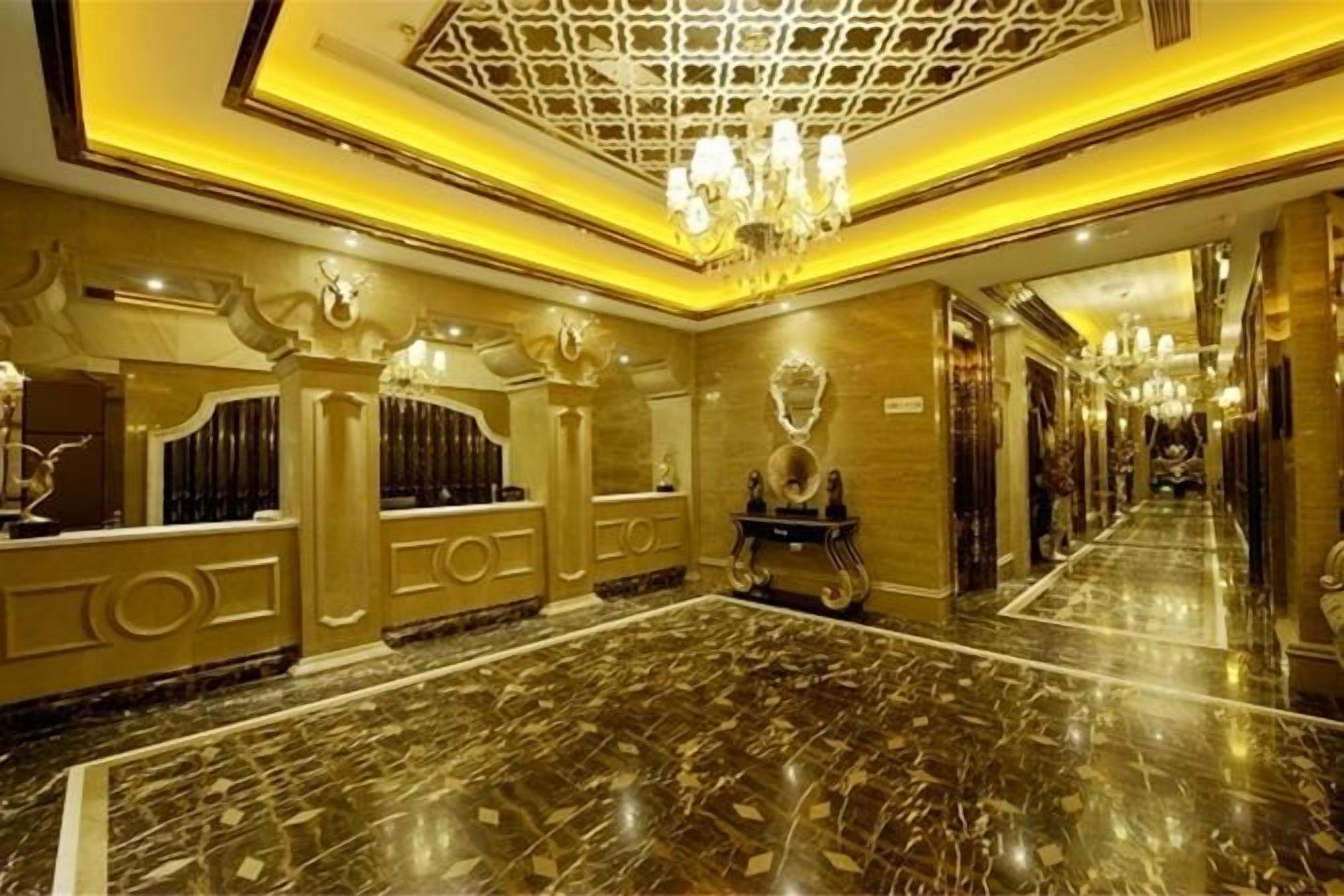 A luxurious hotel lobby with marble flooring, ornate chandeliers, and a grand reception desk.