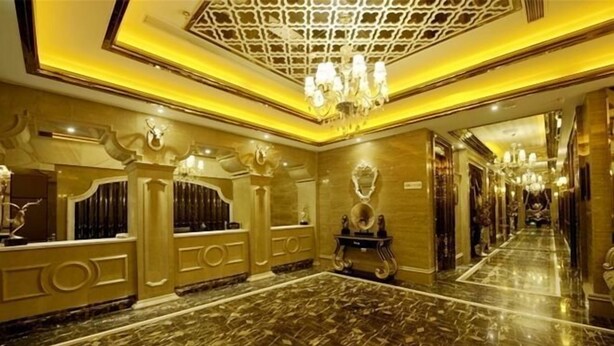 Um corredor luxuoso com piso de mármore, decoração de parede ornamentada e lustres.