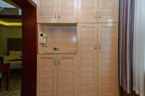 A hotel room with wooden wardrobes, a hairdryer, and a bed with yellow bedding. - Donghua Hotel Bazhong (Bazhong)