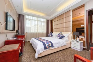 A hotel room with a large bed, a desk, a chair, a TV, and a wardrobe. - Donghua Hotel Bazhong (Bazhong)