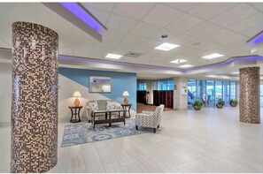 A spacious lobby with a patterned column, a sofa, a chair, and a small table with lamps. - Deluxe Ocean & Sunset View Studio w/kitchen & lots of amenities, great location (Daytona Beach)