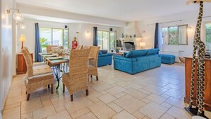 A spacious living area with a dining table, blue sofas, wicker chairs, and a giraffe statue. - Reves de Rives by Interhome (Agay Saint Raphael)