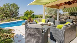 A covered outdoor seating area with wicker furniture and a pool. - Reves de Rives by Interhome (Agay Saint Raphael)