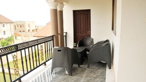 A balcony with wicker furniture and a view of neighboring buildings. - Vesgrah Homes (Kumasi)