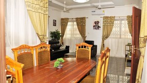 A dining area with a wooden table, four chairs, and a potted plant. - Vesgrah Homes (Kumasi)