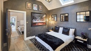 A modern bedroom with a large bed, a skylight, a mirror, and a framed picture on the wall. - Host & Stay | The Stables (Yarm)