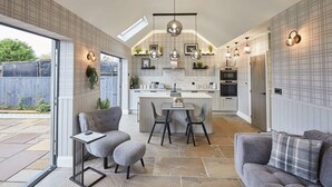 A modern kitchen with a central island, pendant lighting, and a view to the outside. - Host & Stay | The Stables (Yarm)