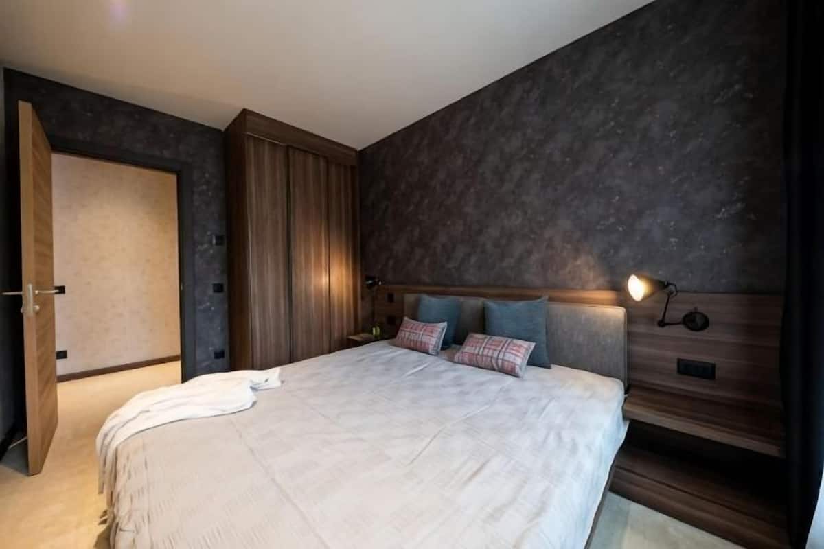 Une chambre avec un grand lit, une armoire et une tĂȘte de lit dotĂ©e dâun Ă©clairage intĂ©grĂ©.