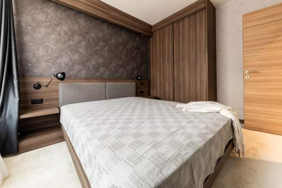 A bedroom with a bed, wooden headboard, bedside tables, and a wardrobe.