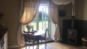 A room with a fireplace, a dining table with chairs, and a window with curtains. - Duck House  (Bodorgan)