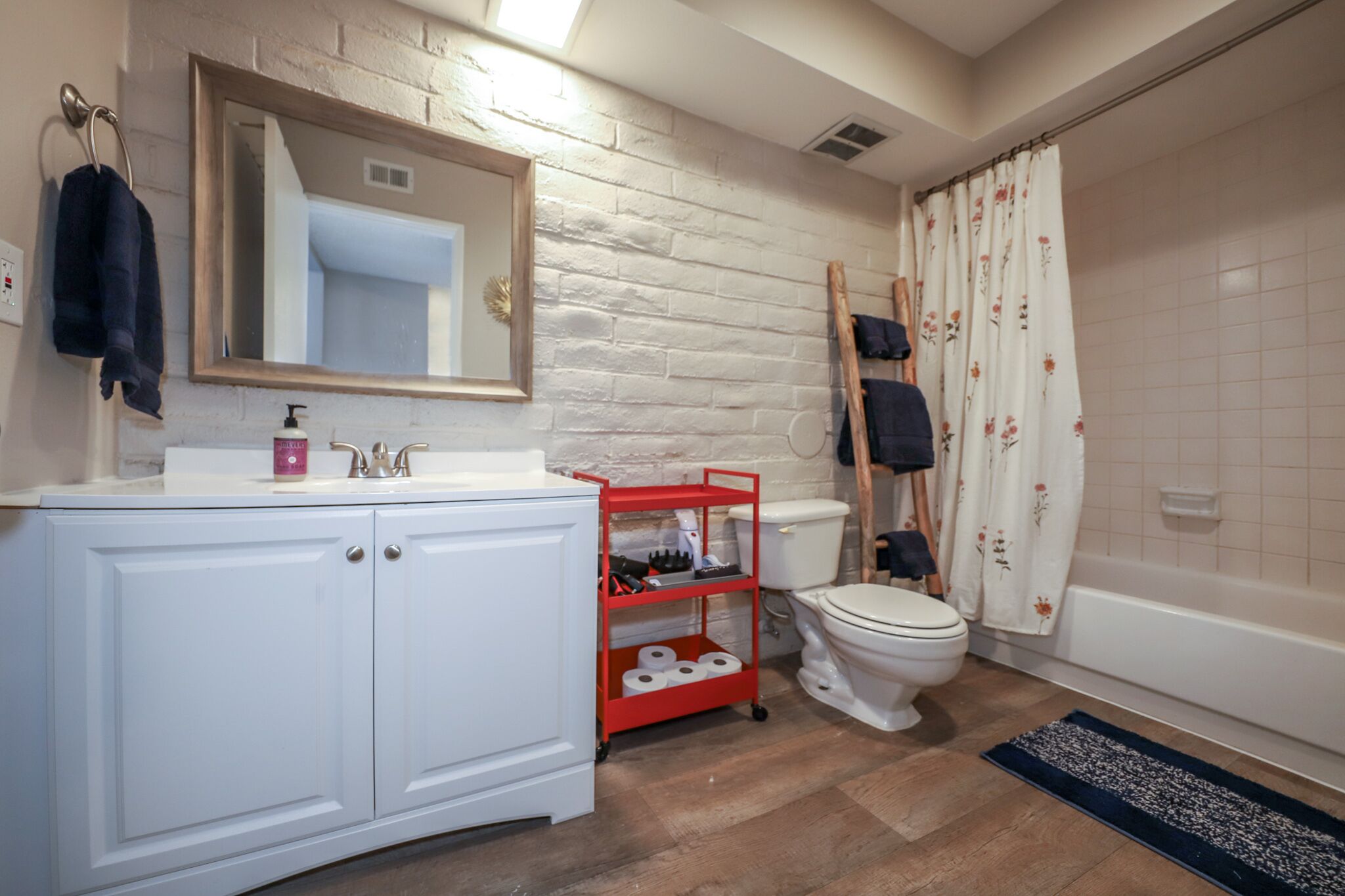 Un baño con tocador blanco, espejo, inodoro y cortina de ducha.