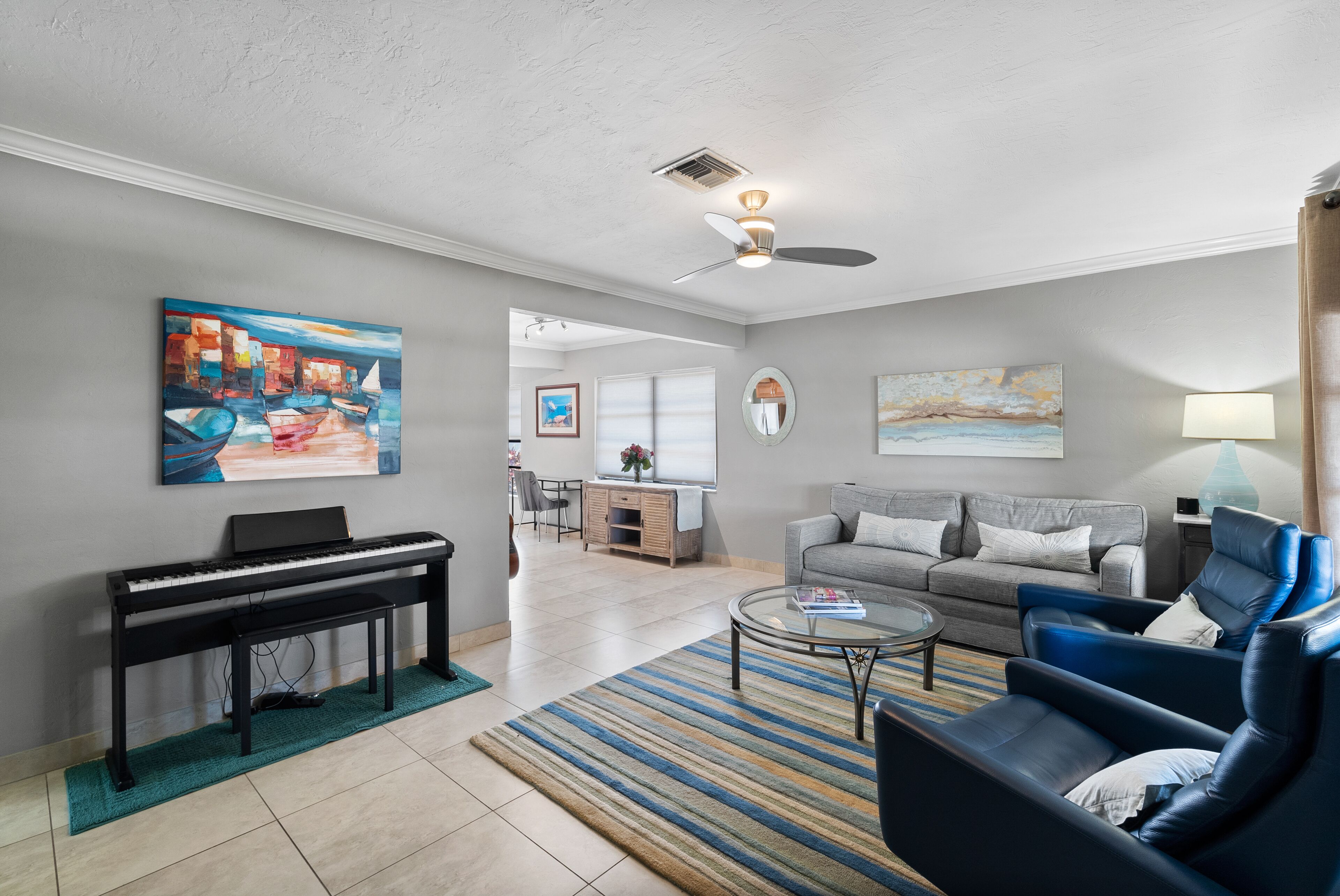 A living room with a piano, a sofa, a coffee table, and artwork on the walls.