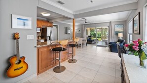 A modern kitchen with a bar area, a dining space, and a living area with a view of the outdoors.