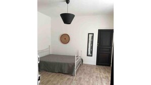 Een kamer met een bed, een deur en een spiegel aan de muur.