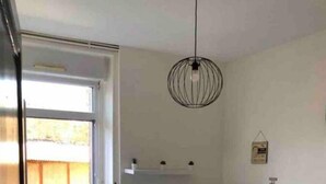 Een kleine keuken met witte kasten, een zwart aanrecht en een hangende lamp.