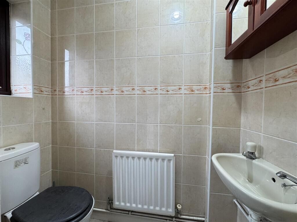 A bathroom with a toilet, a radiator, and a sink.