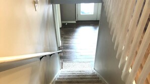 A staircase with wooden steps and white railings, leading to a room with a window and a door. - 4 bedroom lake house at Pickwick (Counce)