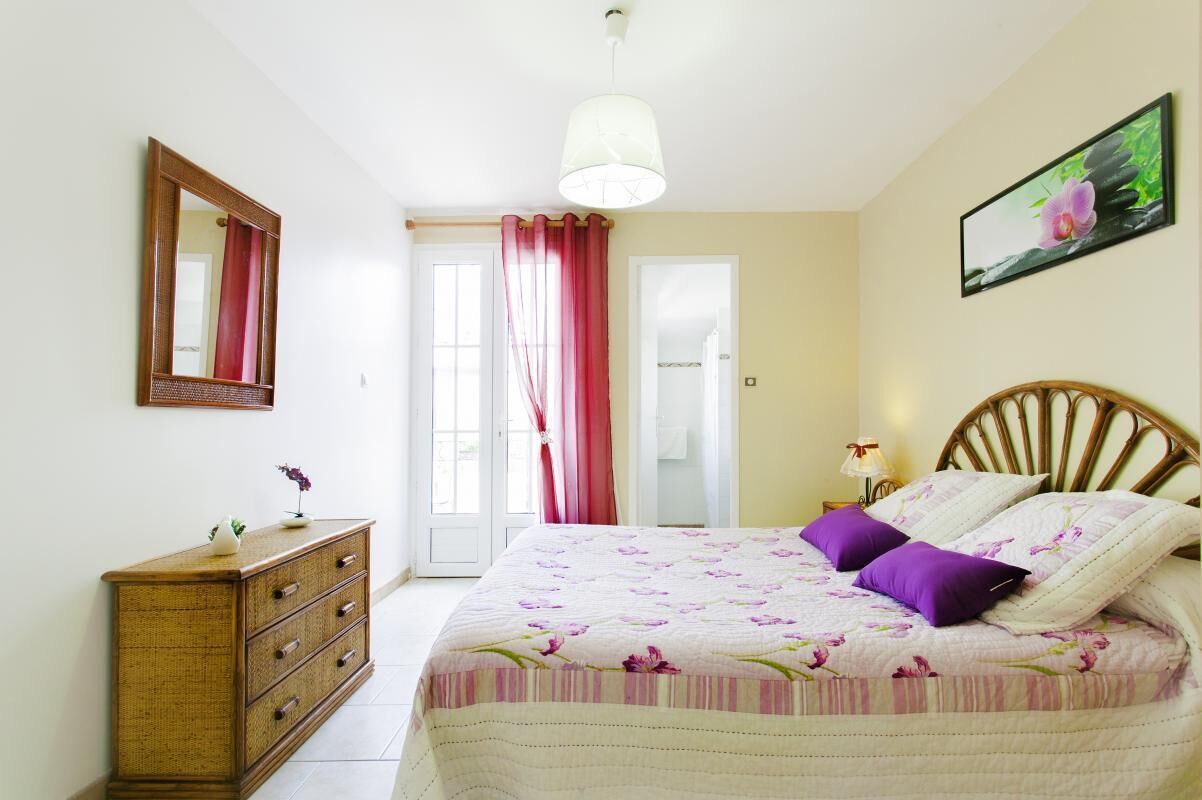 Ein Schlafzimmer mit Bett, Kommode, Spiegel und einem Bild an der Wand.