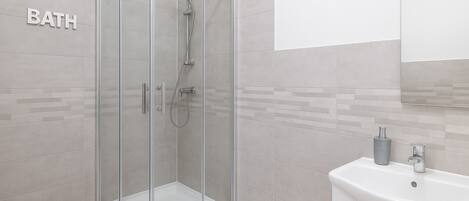 A modern bathroom with a glass-enclosed shower, a sink, and a mirror.