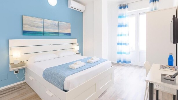 Un dormitorio con cama, mesita de noche y escritorio con silla.