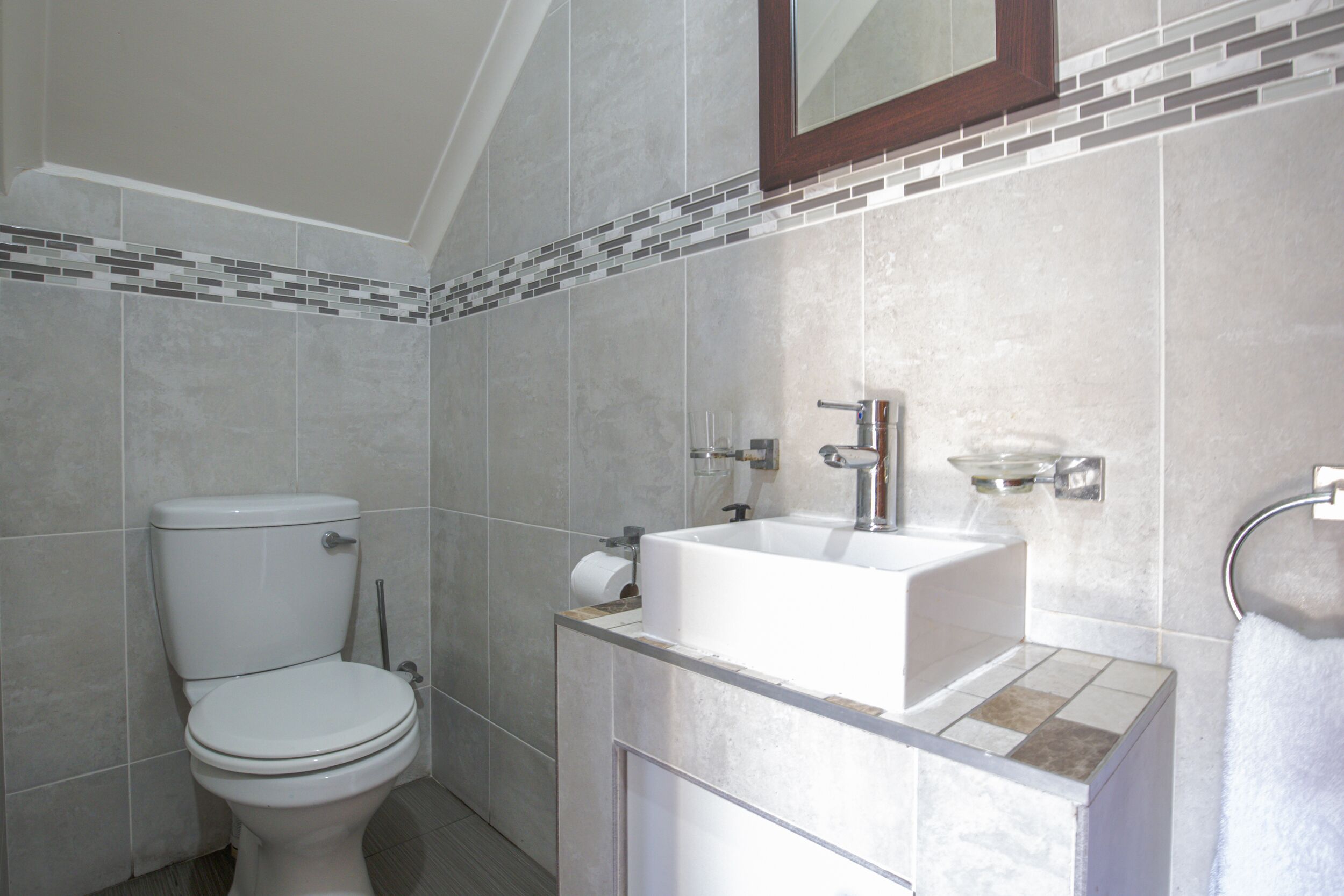 A bathroom with a toilet, sink, and mirror.